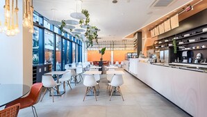 Un espace repas moderne avec des tables et des chaises, un comptoir de cuisine et de grandes fenêtres.