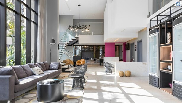 Un vaste espace de vie comprenant un canapé moderne, une table basse et un escalier menant à un niveau supérieur.