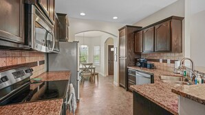 Una cucina moderna con ripiani in granito, elettrodomestici in acciaio inossidabile e mobili in legno scuro.