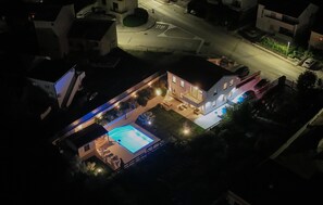 A residential property with a swimming pool, outdoor seating area, and a well-lit patio.