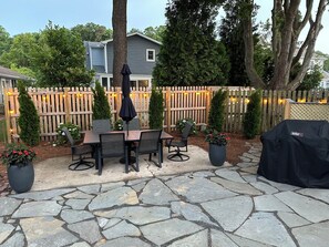 A patio with a stone floor, a table with chairs, and a grill cover. - In-Town Convenience. Family-Friendly 5BR Sleeps 13!   (Rehoboth Beach)