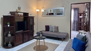 A living room with a sofa, a TV, a cabinet, and a mirror.