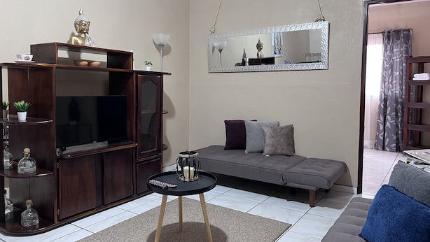 A living room with a TV, sofa, and a small table with a candle.