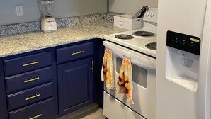 A kitchen with dark blue cabinets, a white microwave, a white refrigerator, and a stove with a water dispenser. -  Lakefront Farmhouse with 2 acres to enjoy -  Fish, Kayak, or launch your boat! (Cochranton)