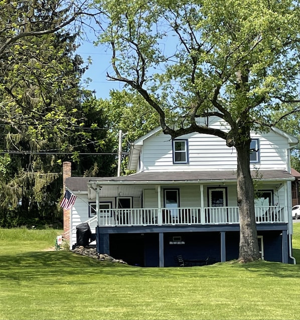 A two-story house with a front porch, a garage, and a large tree in front.