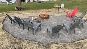 An outdoor seating area with a fire pit and chairs, surrounded by a gravel patio. -  Lakefront Farmhouse with 2 acres to enjoy -  Fish, Kayak, or launch your boat! (Cochranton)