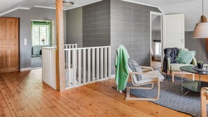 A spacious room with a wooden floor, a white railing, a green towel, a chair, a table, and a lamp. - Flugebacken by Interhome (Sandhem)