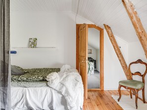 A bedroom with a bed, a chair, a wooden door, and a white ceiling. - Flugebacken by Interhome (Sandhem)