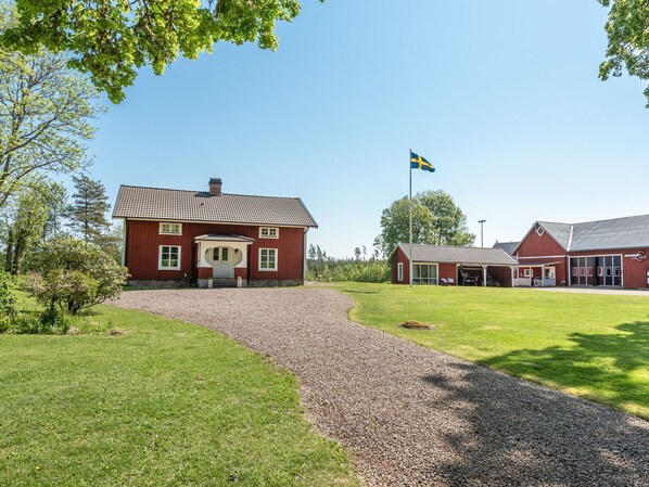 A red building with a gravel driveway and a flag. - Flugebacken by Interhome (Sandhem)