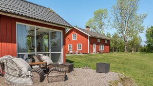 A red wooden house with a large window, a wooden bench, and a gravel area. - Flugebacken by Interhome (Sandhem)