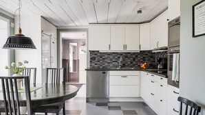 A modern kitchen with white cabinets, a black and white checkered floor, a dining table with chairs, and a hanging light fixture. - Flugebacken by Interhome (Sandhem)
