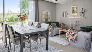 A modern living room with a dining area, large windows, and a view of greenery. - Flugebacken by Interhome (Sandhem)