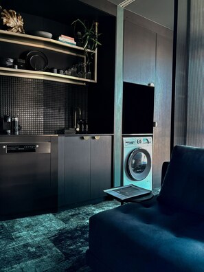 A compact kitchen with a built-in washer and dryer, a dark tiled backsplash, and a minimalist design.