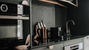 Una cocina moderna con armarios negros, horno empotrado, cafetera y fregadero.