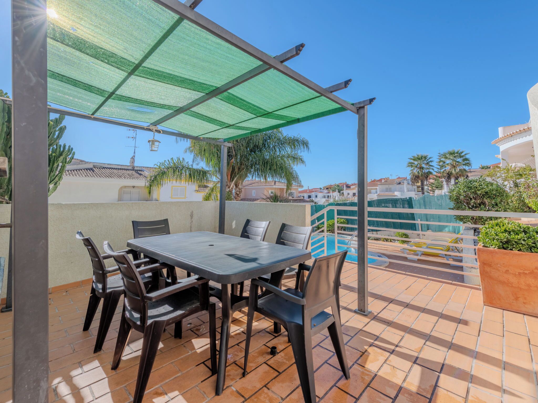 A patio with a table and chairs, a pool, and a view of the surrounding buildings.