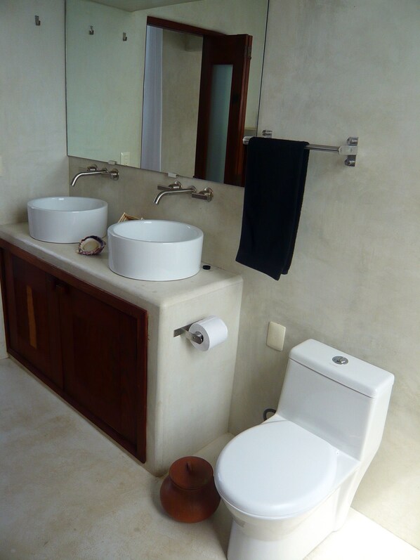 A bathroom with two sinks, a toilet, and a mirror.