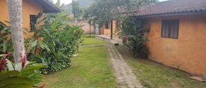 A pathway leading to a building with a tiled roof and a small porch. - Camburi Chalés (São Sebastião)