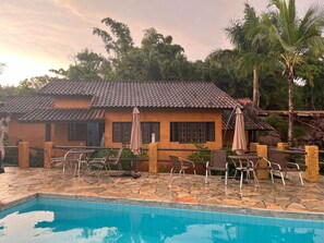 A house with a tiled roof and a swimming pool. - Camburi Chalés (São Sebastião)