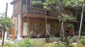 Una casa de madera con balcón, hamaca y jardín.