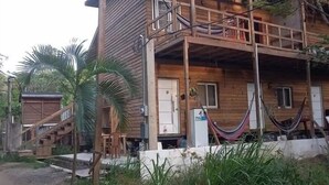 Una casa de madera con balcón, escaleras y una hamaca.