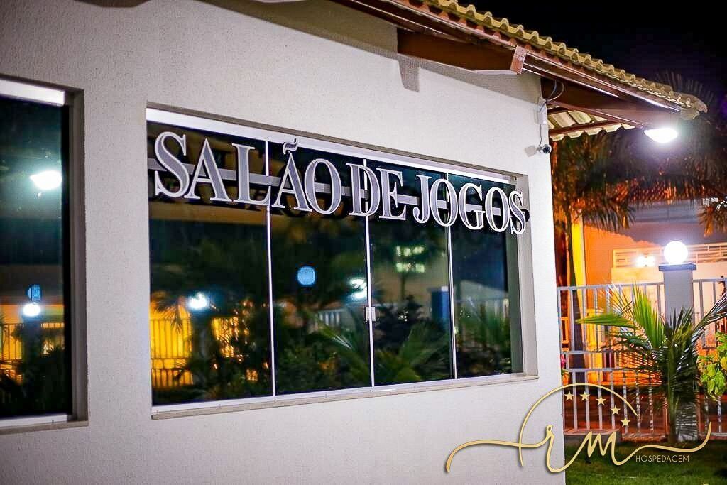 A building with a sign reading "SAIÃO DE JOGOS" and a logo with "HOSPEDAGEM" below it.