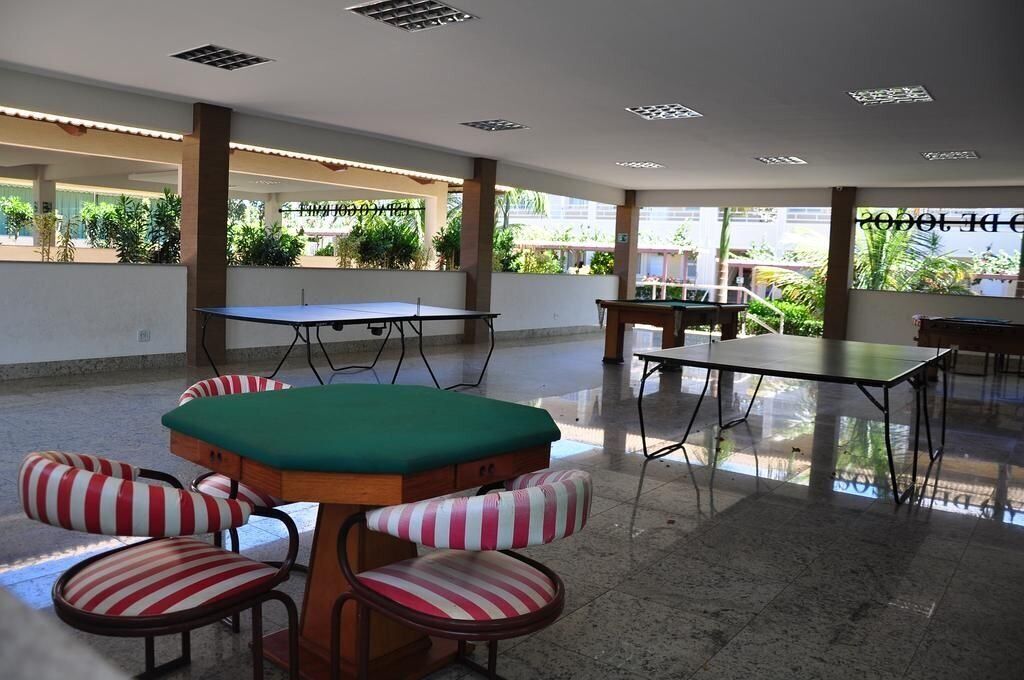 A spacious indoor area with a pool table, a billiards table, and striped cushioned chairs.