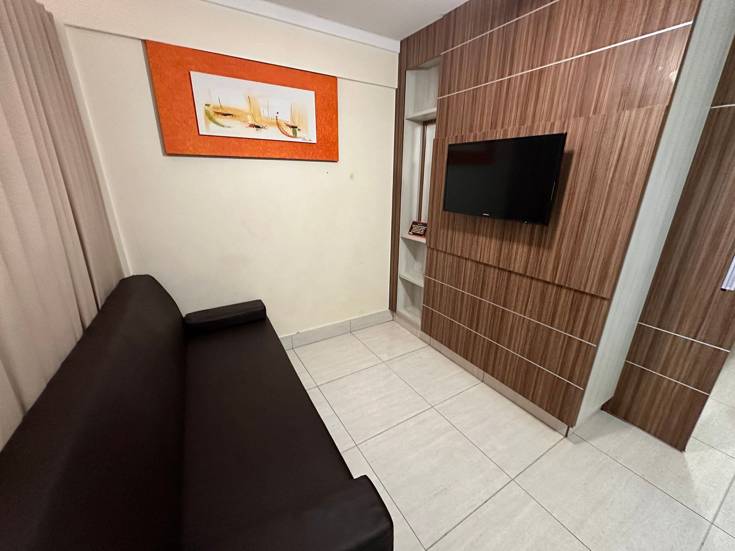 A modern room with a sofa, a mounted TV, and a wooden panel wall.