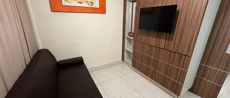 A modern room with a sofa, a mounted TV, and a wooden panel wall.
