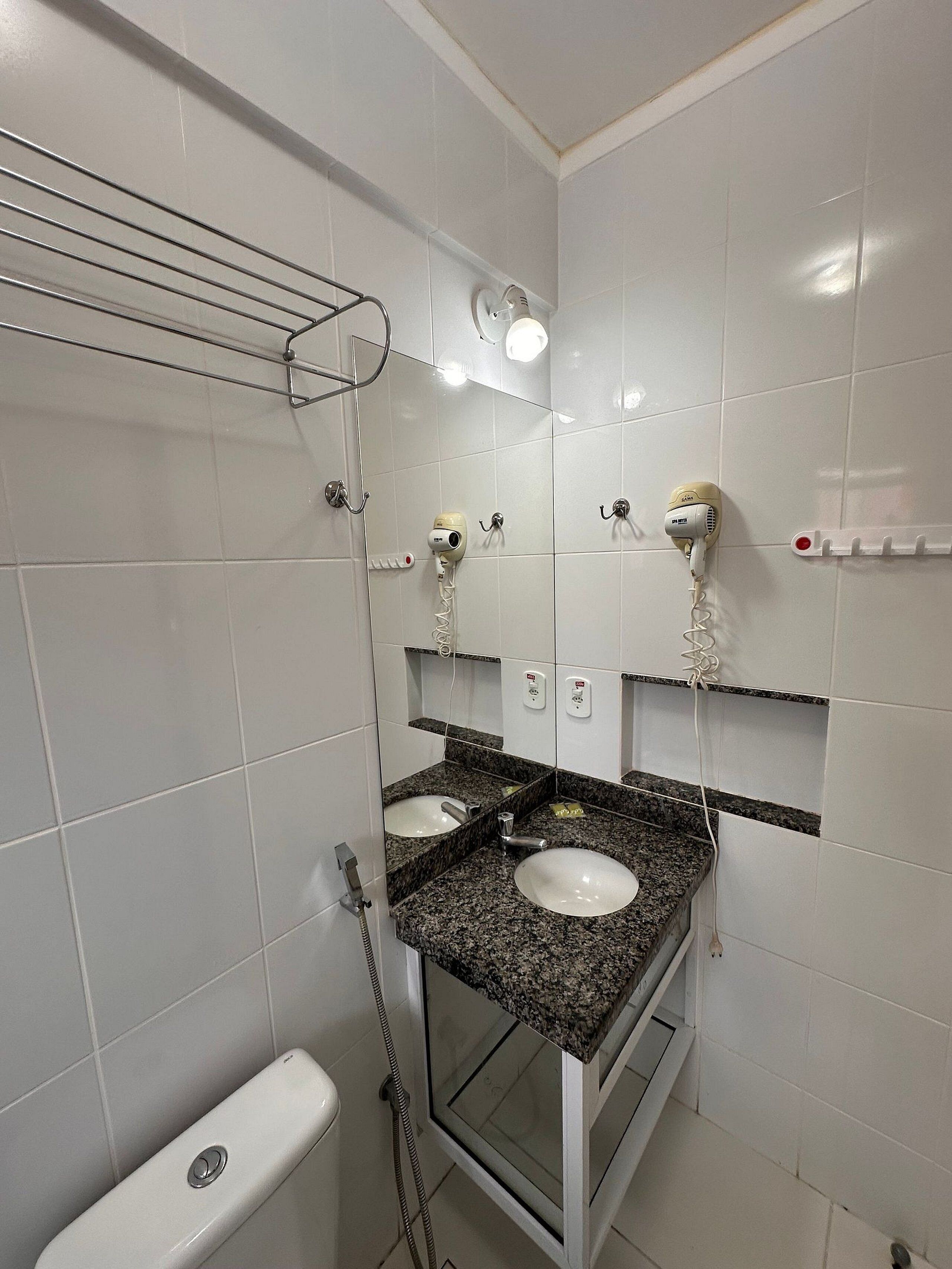 A bathroom with a shower, two sinks, a toilet, and a mirror.