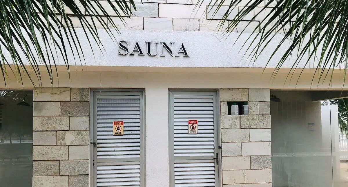 Un edificio con un letrero que dice "SAUNA" sobre dos persianas metálicas cerradas.