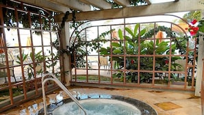 A hot tub in a covered outdoor area with a metal fence and plants. - Lacqua diRoma RM Hospedagem  (Caldas Novas)