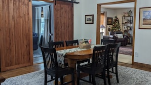 Un coin repas avec une table en bois, des chaises noires et un tapis à motifs.