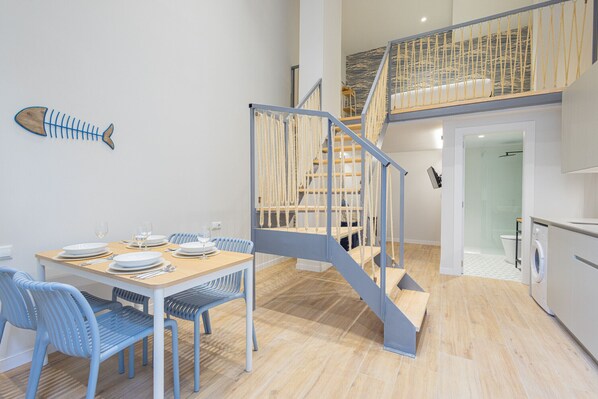 Een moderne keuken met een houten aanrecht, een ingebouwde wasmachine en een trap met een touwbalustrade.