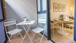 A compact living space with a dining area, two white metal chairs, a small table, and a sofa. - Olive Loft I | AC and WIFI | 10 min City Center (Valencia)