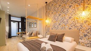 Et moderne hotelværelse med en stor seng, et skrivebord og en stol. Et badeværelse kan anes i baggrunden.