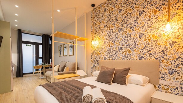 A modern hotel room with a large bed, a desk, and a chair. There is a bathroom visible in the background. - Olive Loft I | AC and WIFI | 10 min City Center (Valencia)