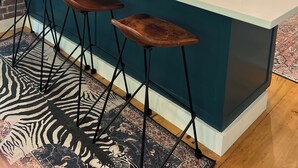 A kitchen with teal cabinets, a large island with bar stools, a brick wall, and a window with a view. - Katama Retreat W Pickle ball Court (Edgartown)