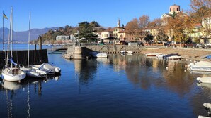 Una marina con barcos amarrados, un muelle de piedra y edificios al fondo.