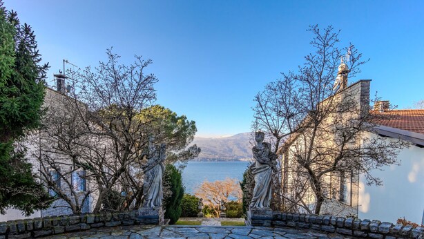 Un sendero de piedra que lleva a una vista de un lago, con estatuas a ambos lados.