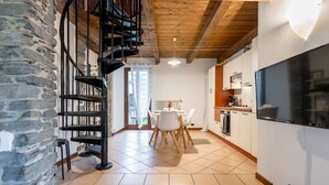 Eine moderne Küche mit großem Fernseher, Holzbalken, Steinwänden und einem Essbereich mit Tisch und Stühlen.