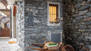 Ein Steinhaus mit Fenster, einer Tür und einem Wagen voller Holz.