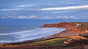 A coastal landscape with a beach, cliffs, and a small settlement. - Penmor -  a holiday home that sleeps 6 guests  in 3 bedrooms (Bude)