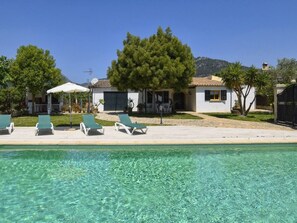 A poolside area with clear water, lounge chairs, and a building with a tiled roof. - Vacation home Tabou by Interhome (Selva)