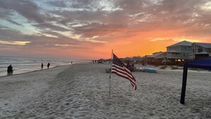 A beach with an American flag, people, and beach houses in the background. - Come Relax and Enjoy the outdoors at our Beautiful Bay front home (Coden)
