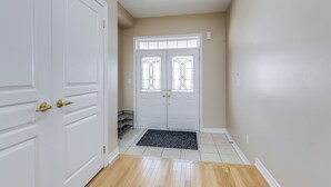 A hallway with a white door, a double door with glass panels, and a wooden floor. - AVID Vacation Palace in Castlemore,Brampton (Brampton)