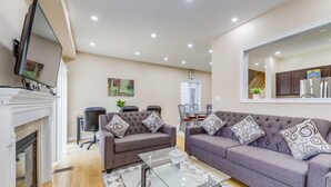 A modern living room with two grey sofas, a glass coffee table, and a fireplace. - AVID Vacation Palace in Castlemore,Brampton (Brampton)