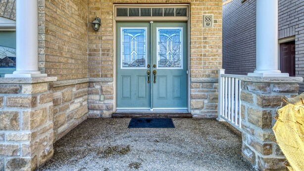 A two-story stone building with a light blue door, a stone porch, and a brick wall. - AVID Vacation Palace in Castlemore,Brampton (Brampton)