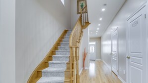 A staircase with wooden railings and carpeted steps leading to a door labeled "Bathroom". - AVID Vacation Palace in Castlemore,Brampton (Brampton)
