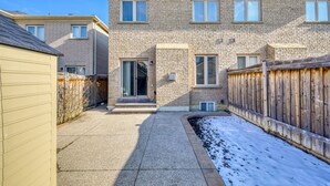A two-story residential building with a brick exterior, a covered patio, and a wooden fence. - AVID Vacation Palace in Castlemore,Brampton (Brampton)