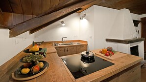 Een keuken met houten kastjes, een zwart inductiefornuis en een presentatie van fruit.